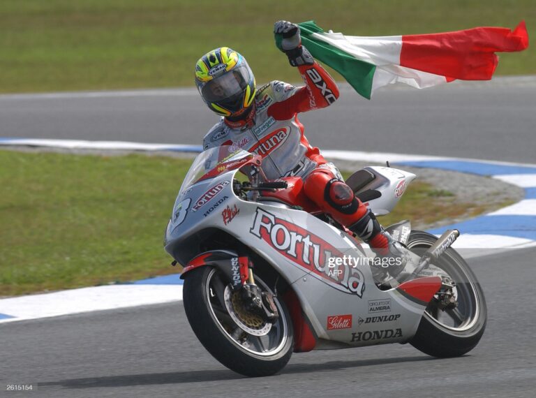 PHILLIP ISLAND, AUSTRALIA:  Roberto Rolfo of Italy waves their national flag on a victory lap following his win in the 250cc Australian Motorcycle Grand Prix in Phillip Island, 19 October 2003. Rolfo has now come within six points of championship leader Manuel Poggiali of San Marino with one race remaining. AFP PHOTO/Keith MUIR  (Photo credit should read KEITH MUIR/AFP via Getty Images)